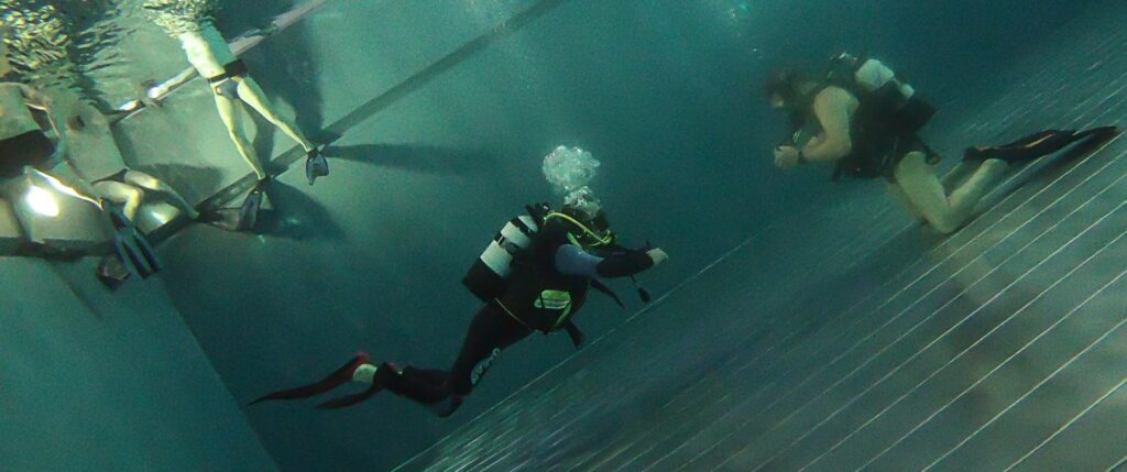 Zwei Gerätetaucher im Schwimmbad bei Tauchübungen.