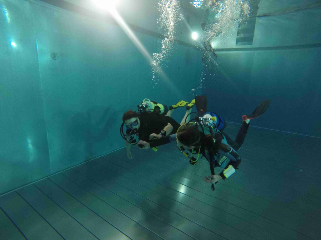 Ein Tauchausbildender mit einem Schnuppertaucher im Schwimmbad
